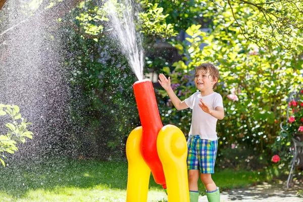 Niño jugando con una manguera de jardín y agua —  Fotos de Stock