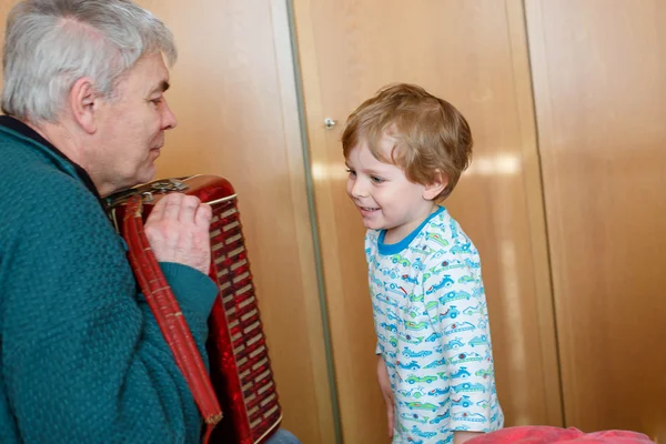 Beetje kid jongen en grootvader spelen muziekinstrument — Stockfoto