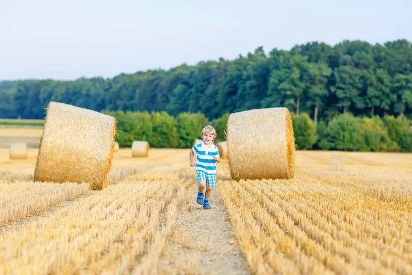 Kleiner Junge, der auf einem Heufeld im Freien spielt — Stockfoto