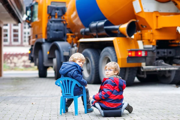 Two kid boys and concrete mixer near house — Stock Photo, Image