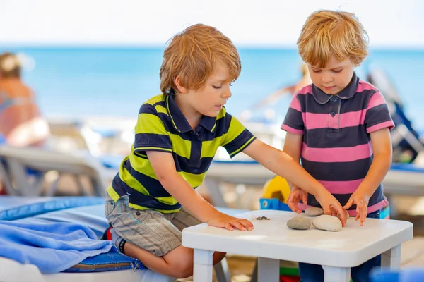 Two little kid boys playing on beach with stones — Stock Photo, Image