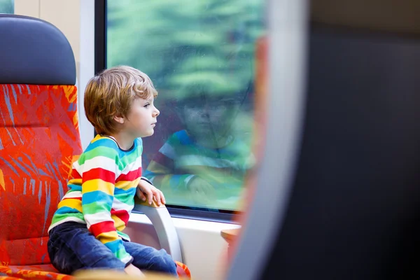 Little boy sitting in train and going on vacations — Stockfoto