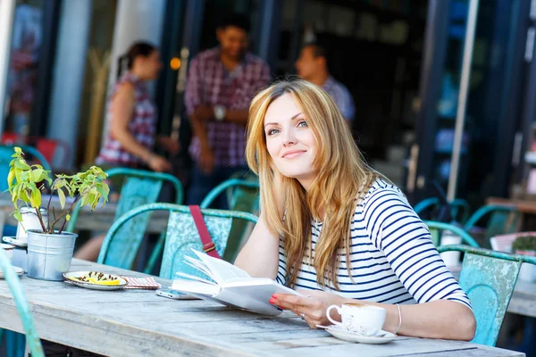 Женщина пьет кофе и читает книги в кафе — стоковое фото