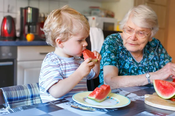 Kleine peuter jongen en overgrootmoeder eten van watermeloen — Stockfoto