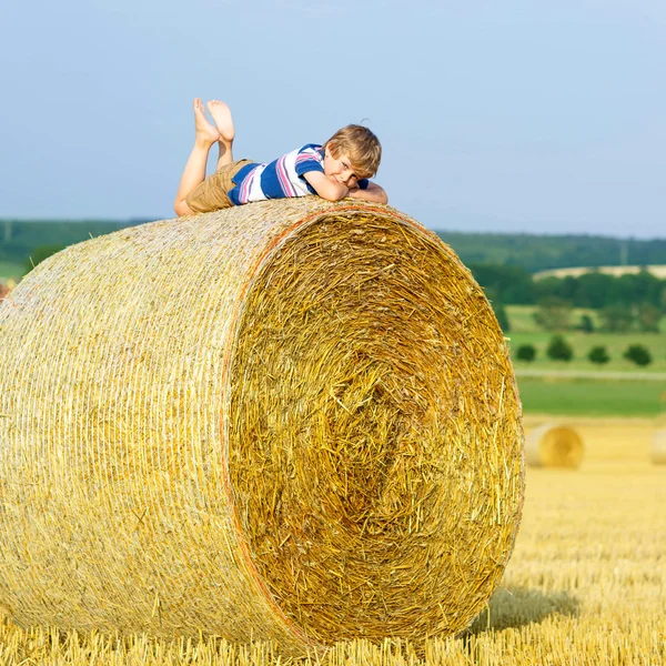 Malý chlapec dítě sedí na balíku sena v létě — Stock fotografie