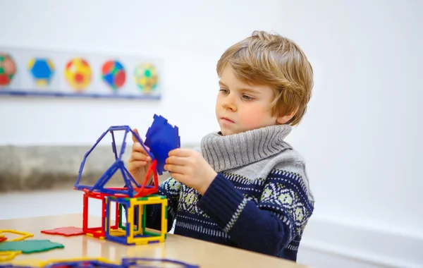 Liten unge pojke bygga geometriska figurer med plast block — Stockfoto
