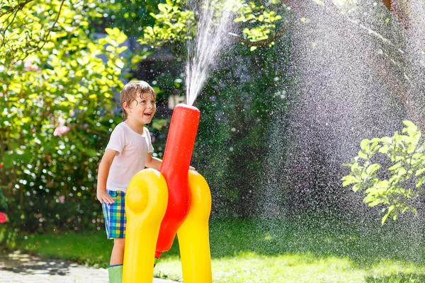 bir bahçe ile oynarken küçük çocuk çocuk hortum ve su