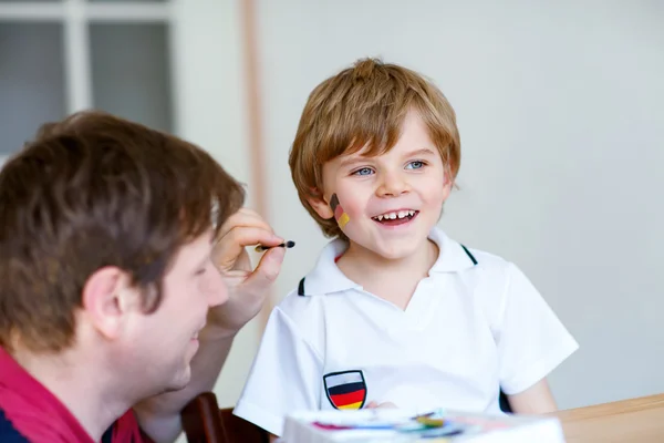 Vater malt Flagge auf das Gesicht eines kleinen Kindes für Fußball oder Fußball — Stockfoto