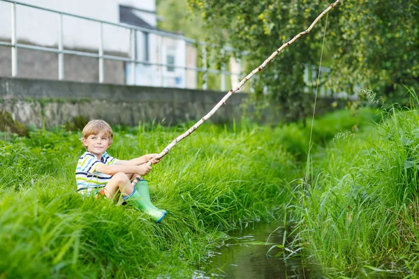 Little kid boy fishing on river with selfmade fishing rod — Stock Photo, Image