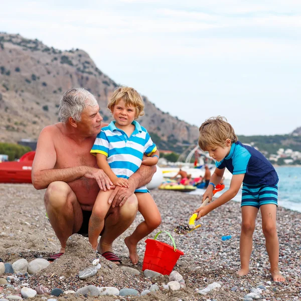 Dědeček a dva malé dítě chlapce na ocean beach — Stock fotografie