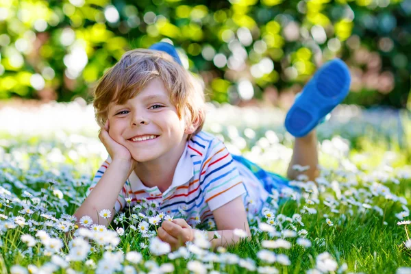 Cute kid boy laying on green grass in summer — ストック写真