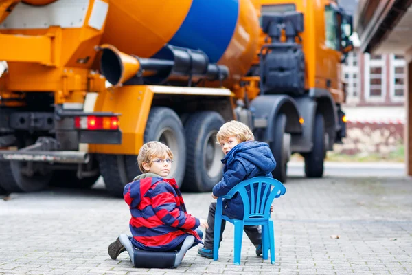 Two kid boys and concrete mixer near house — Stock Photo, Image