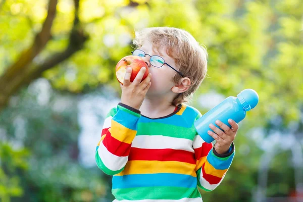 Kleiner Schuljunge mit Büchern, Apfel und Trinkflasche — Stockfoto