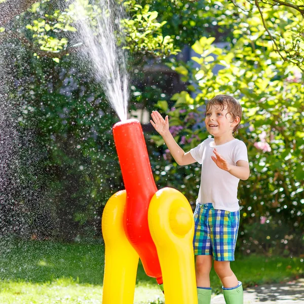 Bir bahçe ile oynarken küçük çocuk çocuk hortum ve su — Stok fotoğraf