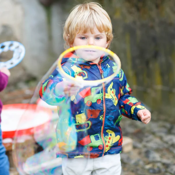 Criança menino soprando bolhas de sabão ao ar livre — Fotografia de Stock