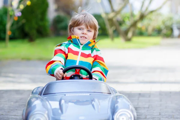 Piccolo bambino in età prescolare guida grande giocattolo vecchia auto d'epoca, all'aperto — Foto Stock
