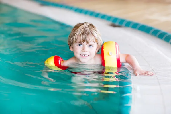 Garotinho com nadadores aprendendo a nadar em uma piscina interior — Fotografia de Stock