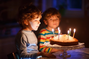Küçük çocuk çocuk ve mumlar doğum günü pastası üzerinde üfleme kardeşim