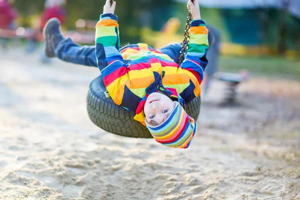 Menino balançando no playground ao ar livre — Fotografia de Stock