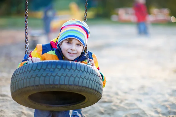 Menino balançando no playground ao ar livre — Fotografia de Stock