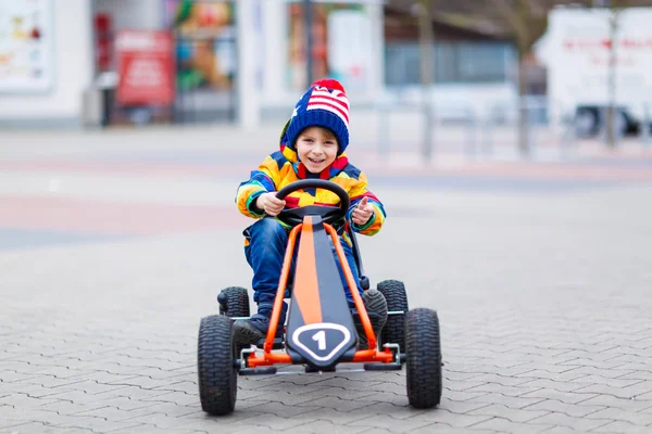 Niño pequeño que se divierte en coche de carreras de juguete al aire libre —  Fotos de Stock