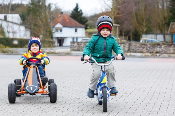 Два маленьких мальчика играют в гоночный автомобиль и велосипед — стоковое фото