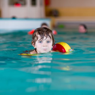 küçük çocuk çocuk swimmies bir kapalı havuzda yüzmek için öğrenme ile
