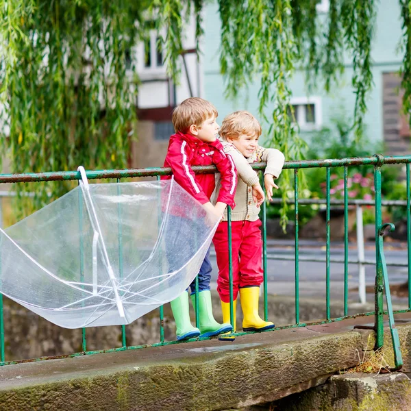 Two little kid boys with big umbrella outdoors — 스톡 사진