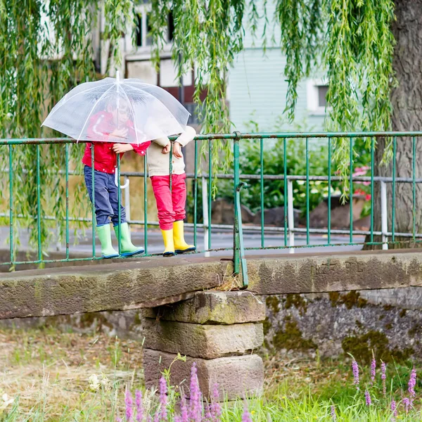 Dos niños pequeños con un gran paraguas al aire libre — Foto de Stock