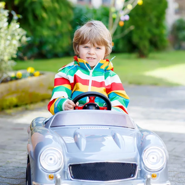 Pequeño niño preescolar conduciendo un gran juguete viejo coche vintage, al aire libre — Foto de Stock