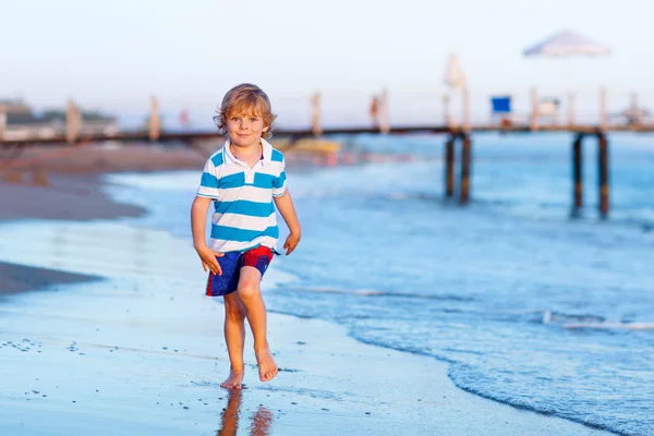 Fröhlicher kleiner Junge, der Spaß daran hat, in oc durch Wasser zu laufen — Stockfoto
