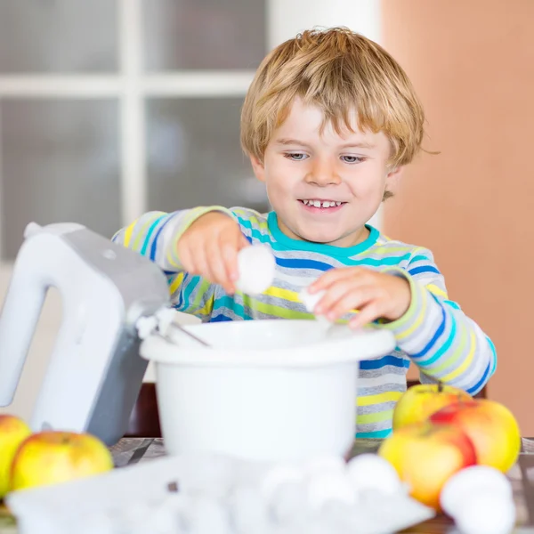 Rolig blond liten pojke baka äppelkaka inomhus — Stockfoto