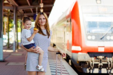 Sevimli küçük kız ve annesi bir tren istasyonu.