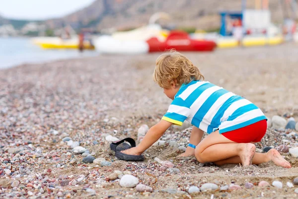 Menino brincando na praia com pedras — Fotografia de Stock