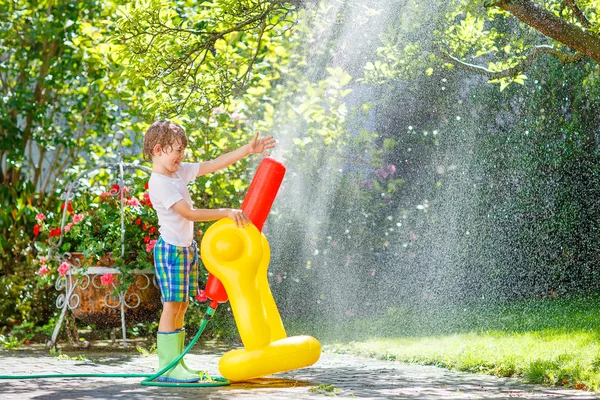 Kleiner Junge spielt mit Gartenschlauch — Stockfoto
