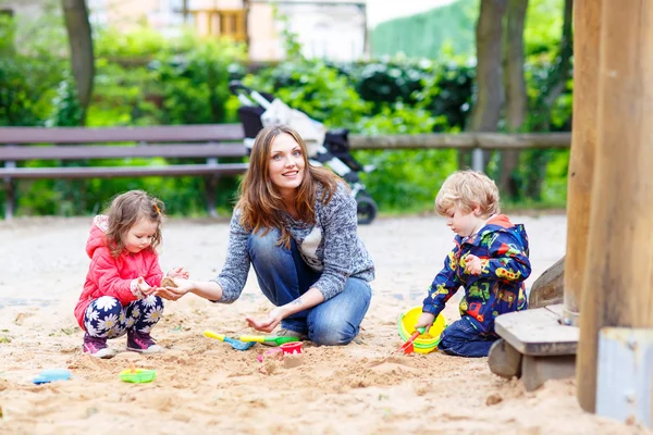 Мать и двое маленьких детей играют на детской площадке — стоковое фото