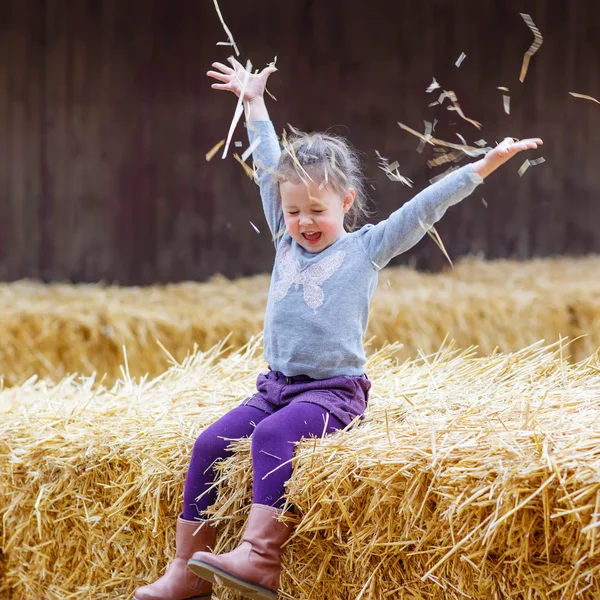 Chica feliz divirtiéndose con heno en una granja —  Fotos de Stock