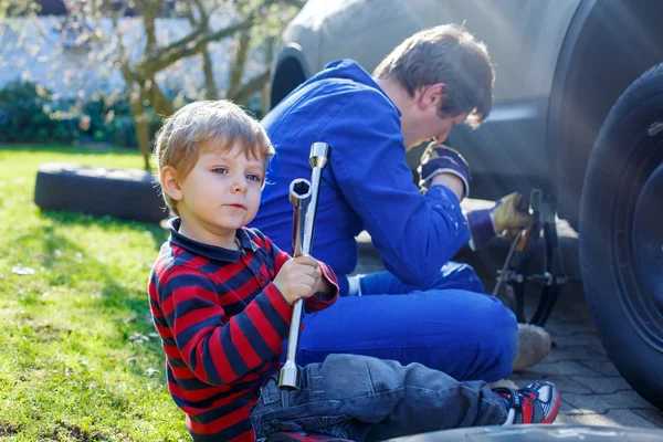 Dítě chlapec a jeho otec, měnit kola na auto — Stock fotografie