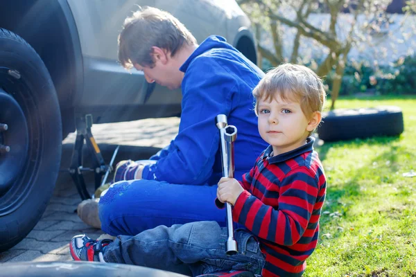 キッド少年と彼の父親は、車のホイールを変更します。 — ストック写真