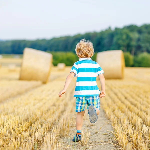 Little kid boy playing on hay field, outdoors — Stock Photo, Image