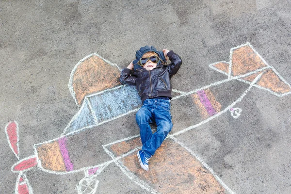 Little boy having fun with airplane picture drawing with chalk — Stock Photo, Image