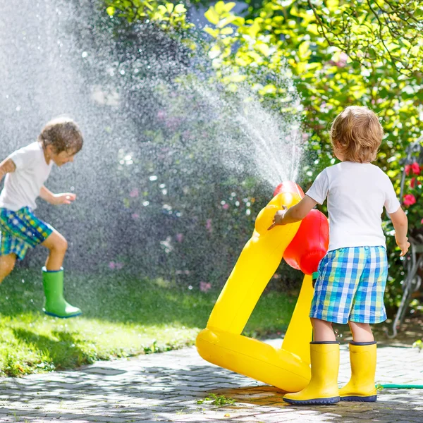 Twee kleine kinderen spelen met tuinslang in de zomer — Stockfoto