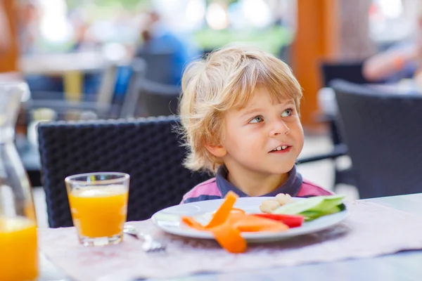 Little kid boy having healthy breakfast in restaurant Stock Picture
