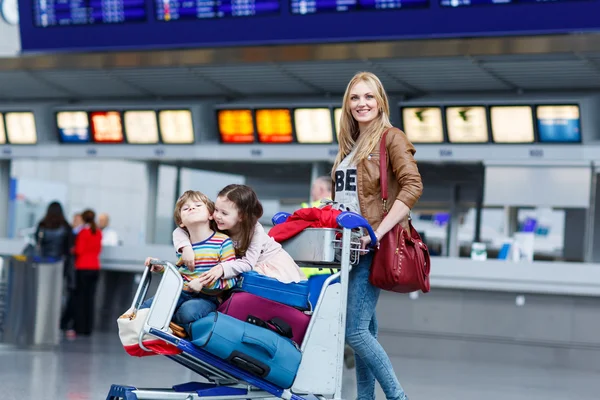 Little girl and boy and young mother with suitcases on airport — Stock Photo, Image