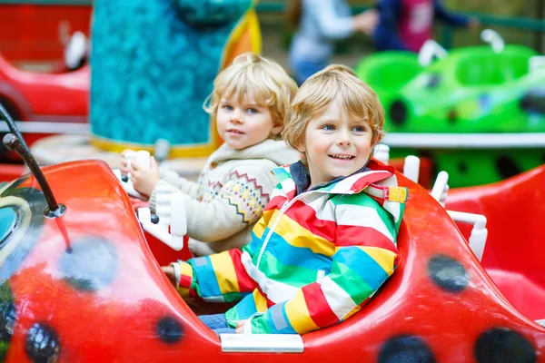Two little kid boys on carousel in amusement park — Stock Photo, Image
