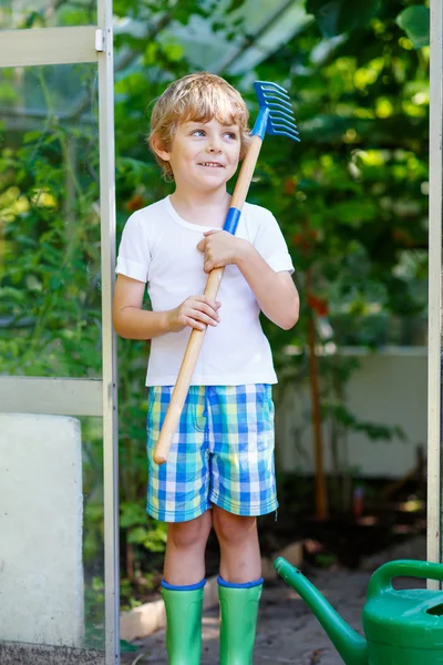 Little kid boy working with garden hoe in greenhouse — Stock Photo, Image