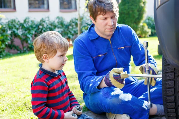 Kleiner Junge und sein Vater wechseln Rad am Auto — Stockfoto