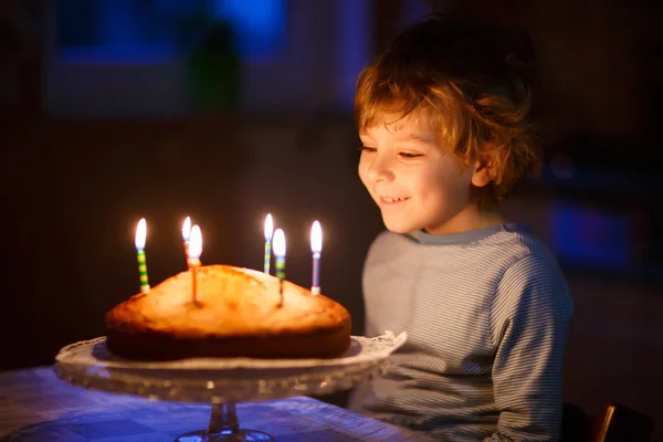 Liten unge pojke blåsa ljusen på födelsedagstårtan — Stockfoto