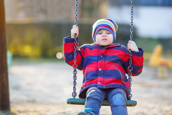 Beetje kid jongen swingen op speelplaats buiten — Stockfoto