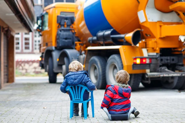 Two kid boys and concrete mixer near house — Stock Photo, Image